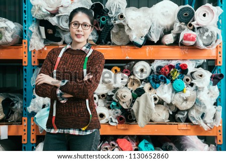 Asian woman stands in the warehouse and crossed her hands and takes a photo with a comfortable smile face to the camera.