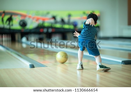 Asian boy play bowling with family day at the sport club,kid throwing rolling bowling ball to target 