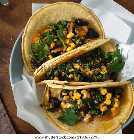 Top view vegetarian tacos made with corn tortillas with black beans, corn, pepper and spicy sauce served on plate