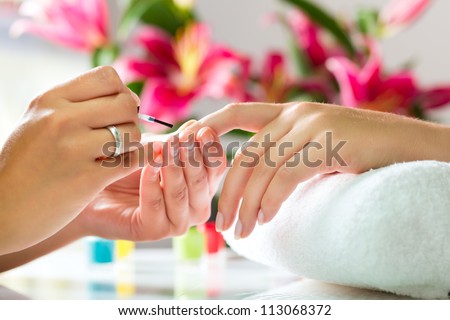 Woman in a nail salon receiving a manicure by a beautician Royalty-Free Stock Photo #113068372