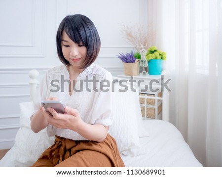 Young woman on bed checking smartphone