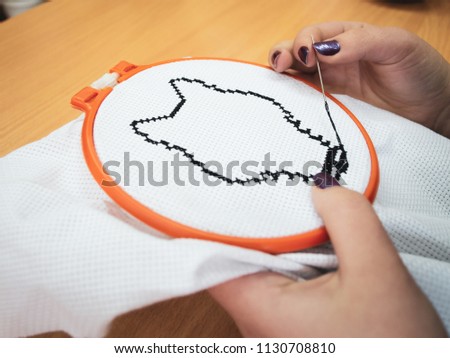Girl embroider wolf or dog on white cloth