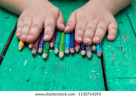 colorful pens and child hand on the green wooden table for school activity time or education concept.creative ideas for child development.