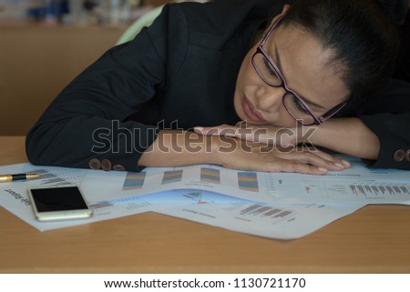Overworked and tired businesswoman sleeping over a desk at work in her office.
