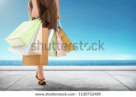 Woman carrying shopping bag walking with seascapes background