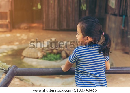 The little girl who was watching the turtles eats in the zoo with sad eyes. selective focus