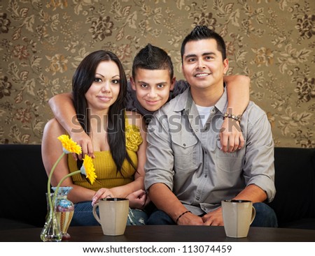 Young smiling Latino family sitting indoors together