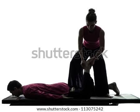 one man and woman perfoming feet legs thai massage in silhouette studio on white background