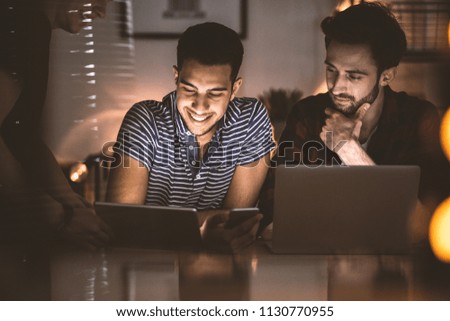 Smiling friends uploading photos on social networking site while using smartphone
