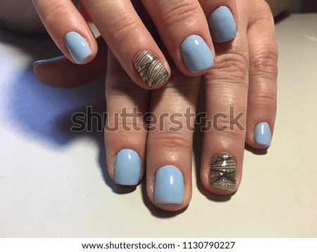 fashionable blue manicure with a black pattern and gold stripes