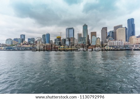 Seattle waterfront and skyline, with the Space Needle showing through the spokes of the Great Wheel ferris wheel in the foreground