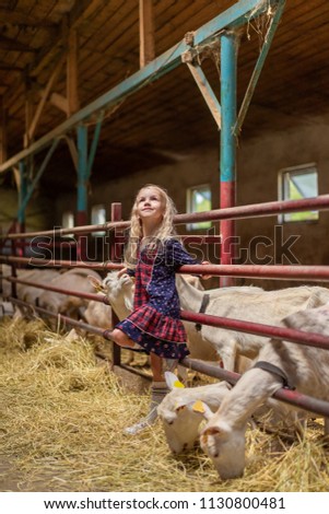 smiling kid leaning on fences in barn and looking up