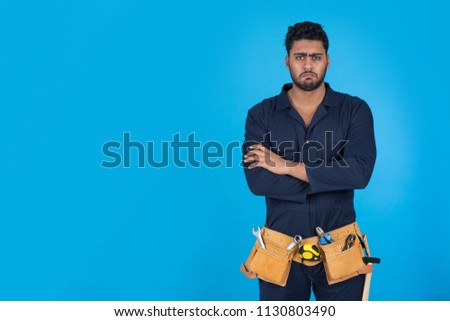 Unsatisfied repairman standing crossed arms with frowning face emotion on blue background.