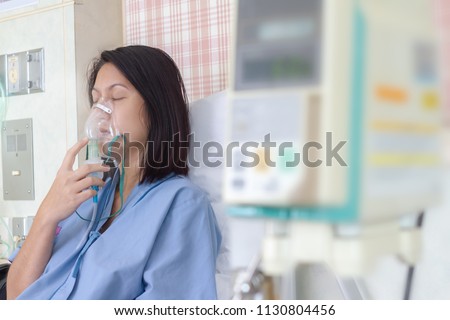 Sick beautiful female in blue cloth hold nasal mask with respiratory problem in hospital room. Asian woman patient inhalation therapy by the mask of inhaler with soft stream smoke from bronchodilator. Royalty-Free Stock Photo #1130804456