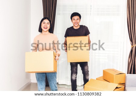 Happy young couple holding box and moving into their new home.House moving and real estate concept