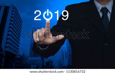 Businessman pressing 2019 start up business icon over modern office city tower, Happy new year concept