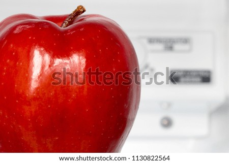 A red apple in an fridge with temperature control on the background. One fresh apple in an refrigerator. Fruits is cooling in storage.