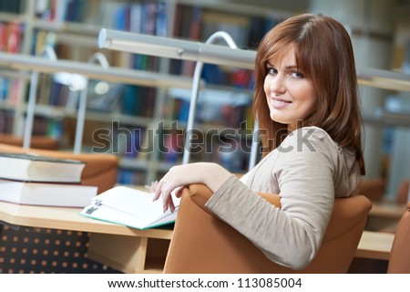 Studying young teenage college student girl  in a library with books