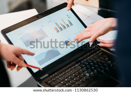 business meeting. problem solving, issue management. troubleshooting. communication, information exchange. executives discussing company results reading papers with graphical data on laptop