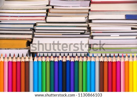 Colorful wooden pencils and piles of books, back to school background concept