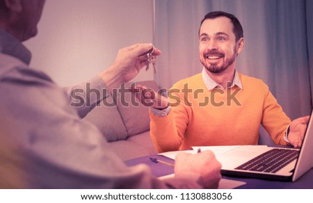 Mature man and young agent sign contract of rent apartments and hand over keys