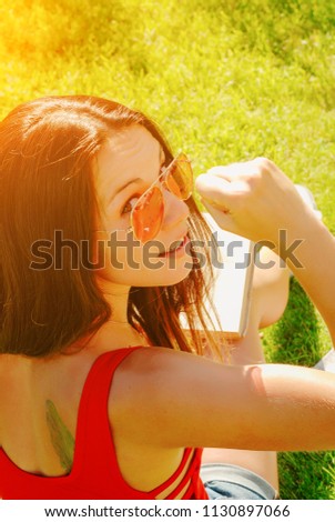 happy young brunette woman reading a book outdoor on a summer day