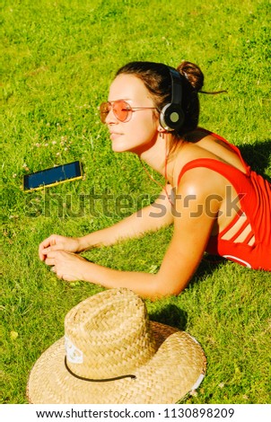 happy young brunette woman listening to the music outdoor on a summer day
