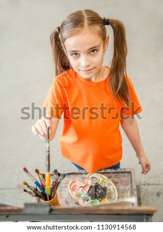 Little girl painter with easel at school. Top view