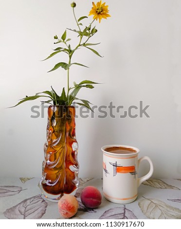 Big cup of coffee with two peaches and vase of yellow flower on the kitchen table. Ethiopian coffee arabica 100%. Copy space. Good morning picture.