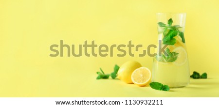 Detox water with mint, lemon on yellow background. Banner with copy space. Citrus lemonade. Summer fruit infused water