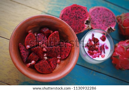 Dragon fruits on wooden background. The fruit has a soft texture and a sweet but unique flavor. It has a attractive color of skin full of edible flesh. This photo can use and food and drink background