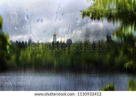 Landscape of the city of Kiev. View of the Dnieper and the Pechersk Lavra. Rainy day. Artistic effect of watercolors and drops of water on the glass.
