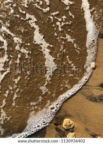 Wet wave over sand on a sandy beach in Greece. Coast between Psaras and Mpoukaris