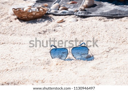 blue sunglasses on the sand of a sea