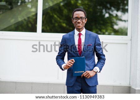 African american happy successful man at suit with diploma at graduation day.