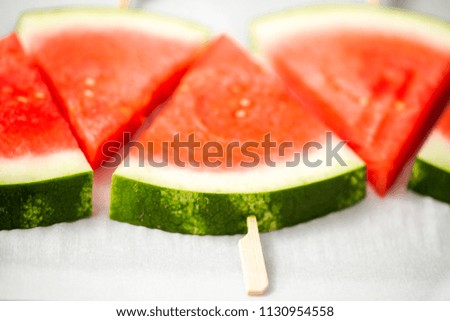 Sliced watermelon in triangle shapes on wooden sticks.