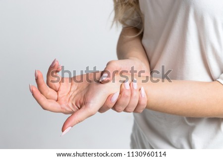 Closeup of female arms holding her painful wrist caused by prolonged work on the computer, laptop.Carpal tunnel syndrome, arthritis, neurological disease concept.Numbness of the hand Royalty-Free Stock Photo #1130960114