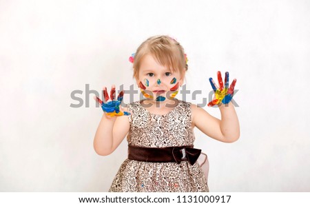 Little beautiful girl draws paints, hands in the paint