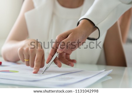 Image of women co-worker hand pointing at business document during discussion at meeting. Colleague pointing right fingers to the business chart, having some questions on report.