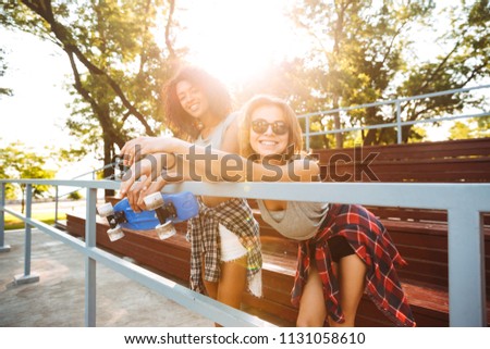 Two excited young girls with skateboard having fun together at the park