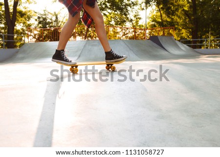 Cropped photo of young woman outdoors with skateboard.