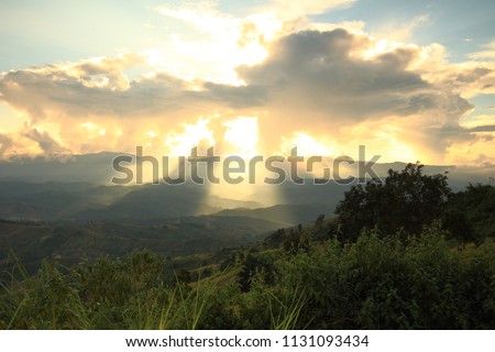 Dramatic god lights passing through clouds and shining on mountain ranges. warm light shower. God hope and dream concept Royalty-Free Stock Photo #1131093434