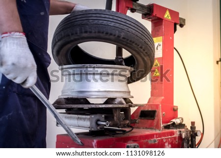 Close-up of a mechanic holding a tire changing device To change new tires for vehicles that come in for service at a repair shop at the factory workplace or at a car repair center.