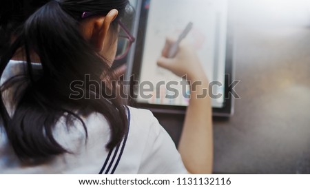 Teenage girl drawing pictures with digital pen and tablet to improve her art skills. Teen's education and learning / Technology's impact on people's lives concept.
