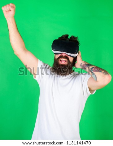 Man with beard in VR glasses, green background. Hipster on enthusiastic face use modern technologies for entertainment. DJ with VR glasses play music, listen headphones. VR musician concept.