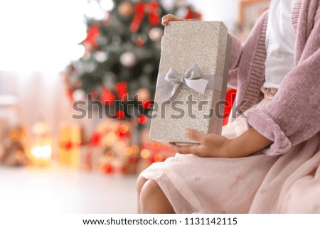 Cute little child with Christmas gift box at home