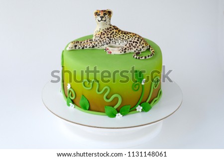 Cake for children's birthday made of green mastic decorated with leopard, flowers, leaves, pattern. Close-up. Cutout. Picture for a menu or a confectionery catalog.