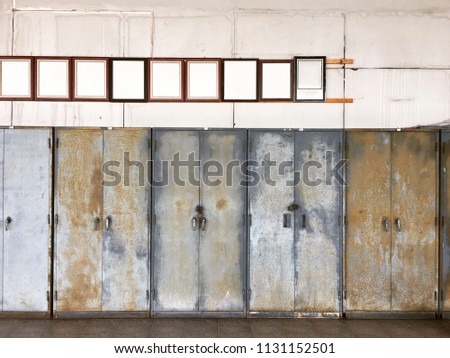 Antique brown wooden photo frame on dirty wall over old steel cabinets that have rust and scratch on them at university hospital in Thailand. Photo of old metal locker.