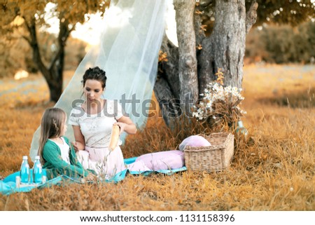 young mother with her daughter at a picnic in the park autumn