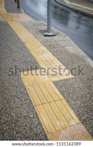 wet, after rain concrete gravel sidewalk Sidewalk guides for blind. Yellow concrete cobblestones on pavement for blind people 